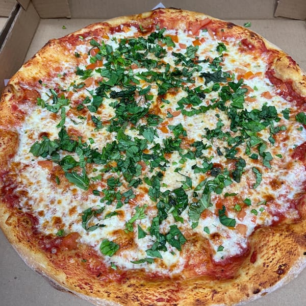 A whole Fat Moe's pizza with melted cheese, diced tomatoes, and fresh basil in a box.