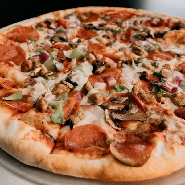 Close-up of a Fat Moe's pizza with pepperoni, sausage, mushrooms, onions, and green peppers.