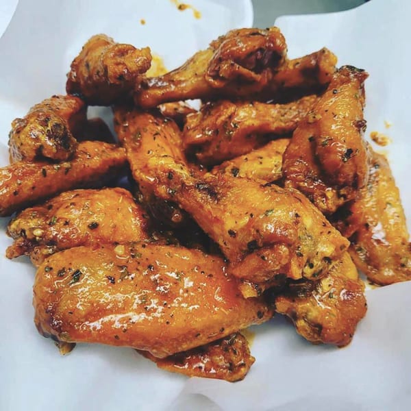 A close-up of a pile of golden-brown, saucy chicken wings from Fat Moe's Pizza & Wings.