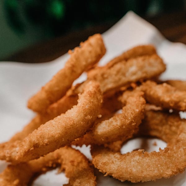 Close-up of golden-brown, crispy onion rings from Fat Moe's Pizza & Wings.